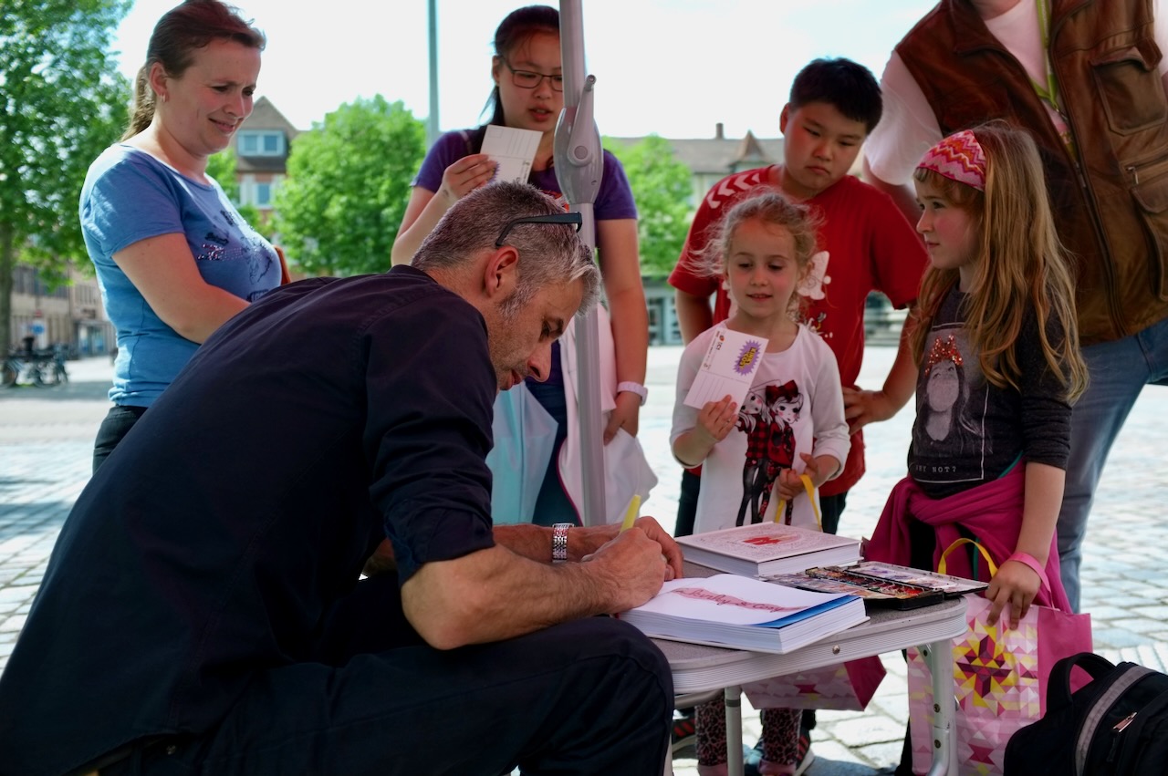 Nix signs books for his readers in front of his container.